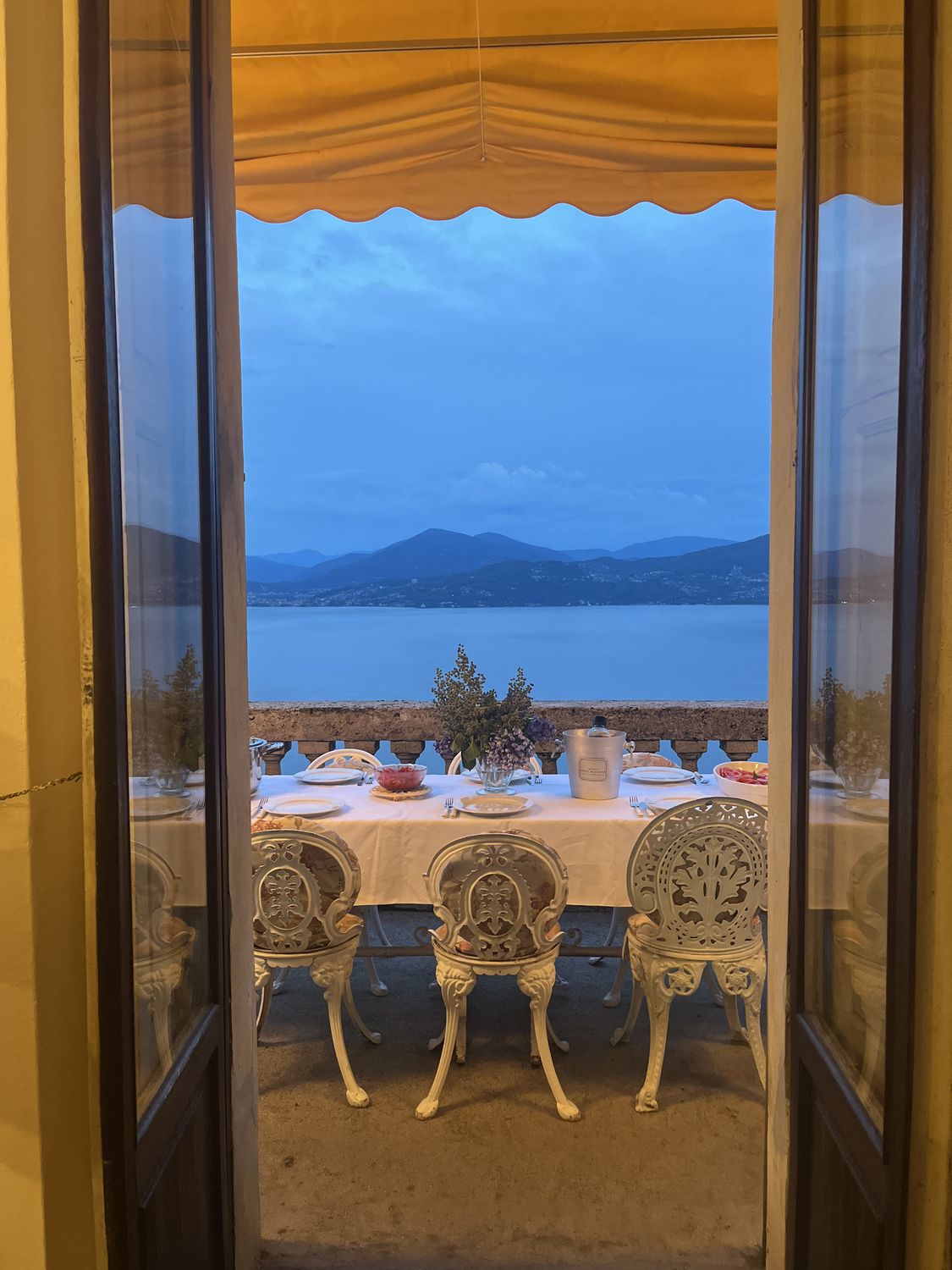 The balcony table at dusk, seen through the open doors