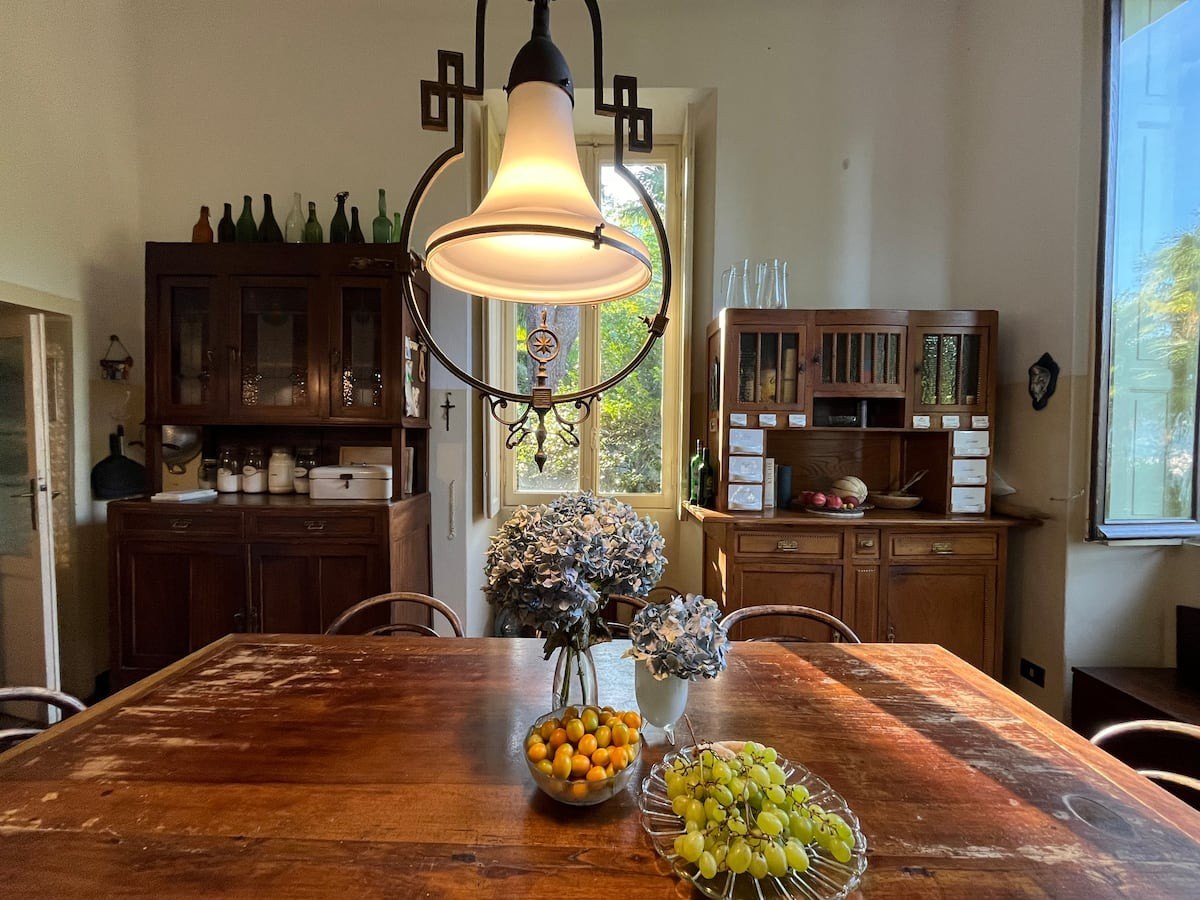 The kitchen table with fruit and hydrangeas under an antique lamp