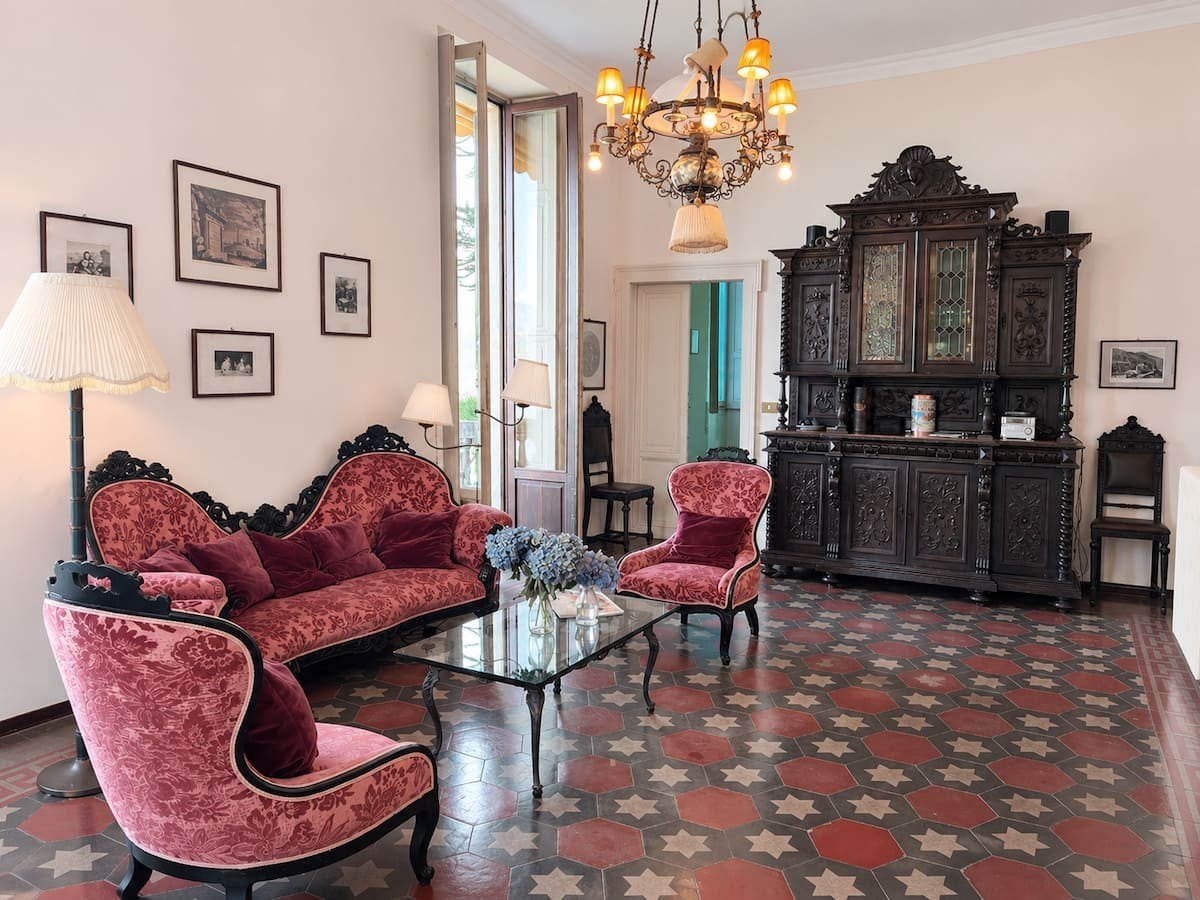 The living room with velvet sofas and a carved cabinet