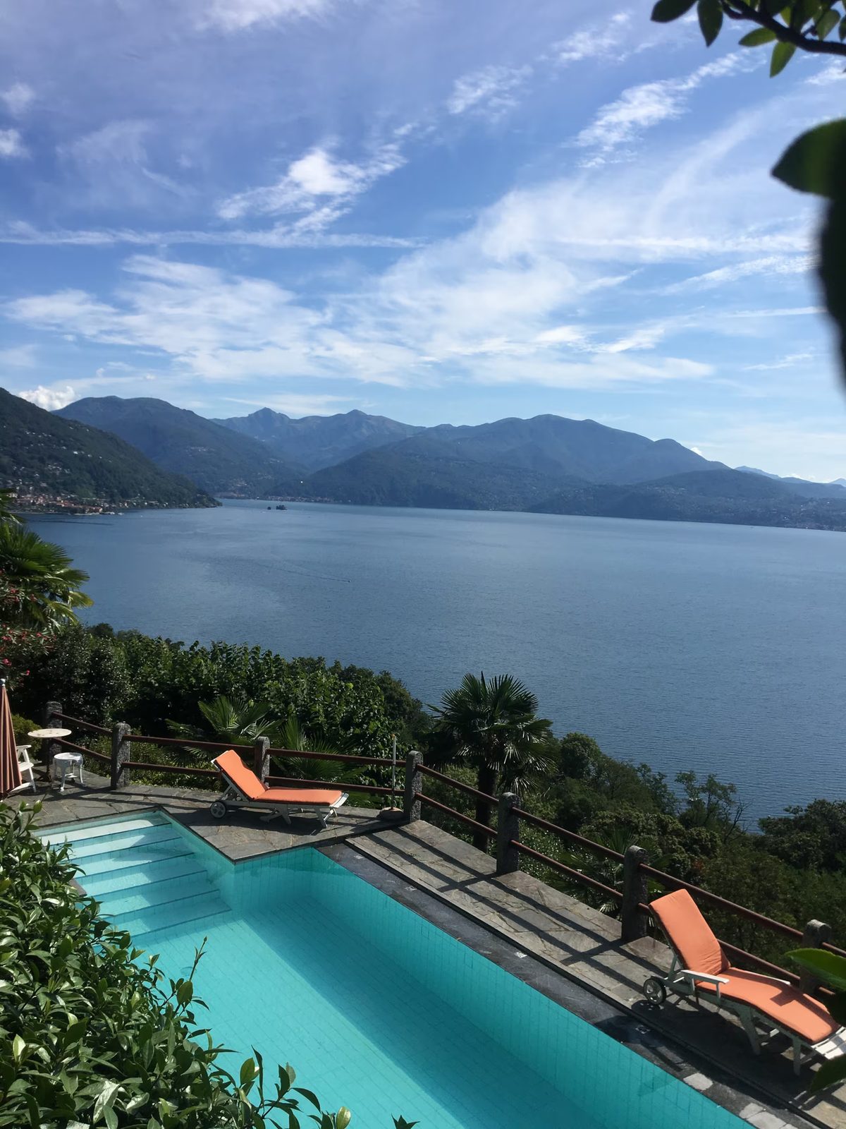 The pool with orange loungers above the lake and mountains